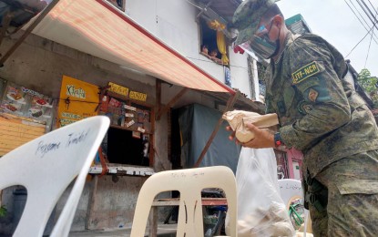 <p><strong>HOT MEALS.</strong> A member of the AFP's Joint Task Force-National Capital Region (JTF-NCR) puts hot meals packs on chairs outside communities in Metro Manila on Thursday (Aug. 12, 2021). The JTF-NCR, in cooperation with other military units and non-government organizations, has so far provided 12,000 hot meals to residents in the region which is under enhanced community quarantine. <em>(Photo courtesy of JTF-NCR)</em></p>