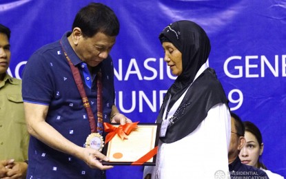 <p><strong>OWNERS.</strong> President Rodrigo Duterte hands a Certificate of Land Ownership Award to a beneficiary at Lagao Gymnasium in General Santos City on June 13, 2019. More than 20,000 hectares of agricultural land were distributed in Soccsksargen that day. <em>(PCOO photo)</em></p>