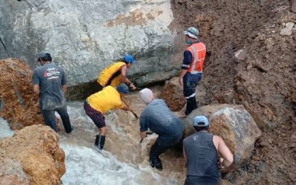 <p><strong>MANUAL DIGGING</strong>. Government and volunteer emergency responders manually dig under a boulder where two miners were believed to have taken refuge when a landslide occurred in the area. The Department of Social Welfare and Development delivered about 50 family food packs to aid the rescuers and a tent where they can take refuge in case of rain. (<em>PNA photo by Dionisio Dennis Jr.</em>) </p>