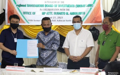 <p><strong>VENTURE</strong>. RBOI-BARMM Chairman Ishak Mastura (left) and BTA Parliament Member Suharto Ambolodto (2nd from left) show the MOA they inked with local investors over the weekend for the establishment of a 5,000-hectare banana plantation in Kabacan, North Cotabato. The plantation will be set up in adjoining villages under the BARMM in Kabacan town. (<em>Photo courtesy of BOI-BARMM)</em></p>