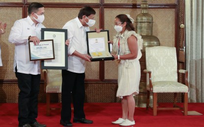 <p><strong>MEDAL OF MERIT.</strong> President Rodrigo Roa Duterte bestows weightlifter Hidilyn Diaz with the Presidential Medal of Merit for winning the country’s first Olympic gold medalist in Tokyo during the awarding ceremonies at the Rizal Hall in Malacañan Palace on Monday (Aug. 23, 2021). Diaz also received PHP10 million as mandated by law, PHP5 million for breaking the Olympic record, an additional PHP3 million from the Office of the President (OP) and a house and lot in Zamboanga City. <em>(Presidential photo by Toto Lozano)</em></p>
