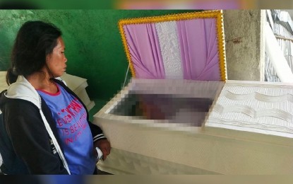 <p><strong>IN MOURNING</strong>. Jocelyn Romadora stands beside the coffin of her husband, Ambrosio, who died in a clash with soldiers on Aug. 18 in Southern Leyte in this Aug. 22, 2021 photo. The mother is also worried about the fate of her son hiding in the mountains fleeing from government forces.<em> (Photo courtesy of Philippine Army)</em></p>
