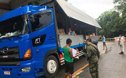 <p><strong>BORDER CHECKPOINT</strong>. A police officer inspects documents of a cargo truck passing through the border checkpoint in Pagudpud-Sta. Praxedes boundary in Ilocos Norte. To contain the surge of Covid-19 cases in the province, border control measures have been tightened particularly on the entry of cargoes. (<em>PNA photo by Leilanie G. Adriano</em>) </p>