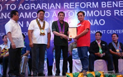 <p><strong>RIGHTFUL OWNER.</strong> President Rodrigo Duterte leads the distribution of 815 Certificates of Land Ownership Award for Bangsamoro Autonomous Region in Muslim Mindanao beneficiaries at Shariff Kabunsuan Cultural Complex, Bangsamoro Government Center in Cotabato City on Dec. 23, 2019. He was assisted by (from left) Bangsamoro Interim Chief Minister Ahod Ebrahim and Agrarian Reform Secretary John Castriciones. <em>(Presidential photo)</em></p>