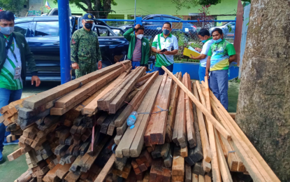<p><strong>SEIZED.</strong> Police and environment officials inspect the forest products believed to be illegally cut and abandoned on Thursday (Sept. 16, 2021) in Parang, Maguindanao. A total log ban has been implemented in all areas under BARMM, which includes Maguindanao, since 2015. <em>(Photo courtesy of Maguindanao MENRE Office)</em></p>