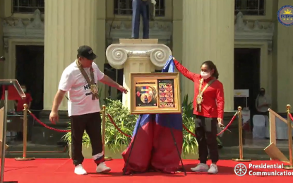 <p><strong>OLYMPIC GOLD WINNER STAMP.</strong> Philippines' first Olympic gold medalist weightlifter Hidilyn Diaz unveils the newly released Philippine Postal Corporation (PHLPost) stamp celebrating her historic Olympic triumph on Saturday (Sept. 18, 2021). Postmaster General and CEO Norman Fulgencio assisted Diaz. <em>(Screengrab from RTVM)</em></p>