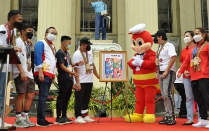 <p><strong>VACCINE ADVOCATES.</strong> The Philippine Post Office launches commemorative stamps featuring front-liners in the fight against Covid-19 and the four Tokyo Olympics medalists at the Manila Central Post Office on Saturday (Sept. 18, 2021). The event was graced by (from left) boxers Eumir Marcial and Carlo Paalam, Philippine Olympic Committee president and Cavite Representative Bambol Tolentino, boxer Nesthy Petecio, Postmaster General Norman Fulgencio, the Jollibee mascot, Presidential Assistant for the Visayas Secretary Michael Lloyd Dino, Philippine Sports Commissioner Celia Kiram, and weightlifter Hidilyn Diaz, the country’s first Olympic gold medalist. <em>(Photo courtesy of PHLPost)</em></p>
