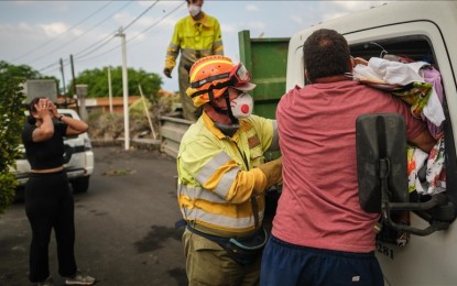 <p><strong>VOLCANIC ERUPTION.</strong> Officials help during an evacuation process as Mount Cumbre Vieja continues to erupt in El Paso, spewing out columns of smoke, ash and lava on the Canary island of La Palma on Sept. 21, 2021. Officials said the volcanic eruption on the Spanish Canary Island of La Palma has destroyed around 100 homes, large swathes of agricultural land, roads, and businesses. <em>(Andres Gutierrez - Anadolu Agency)</em></p>