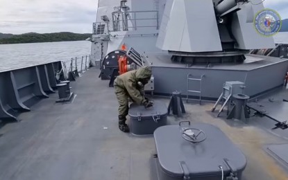 <p><strong>CHEMICAL ATTACKS DEFENSE.</strong> A crew member of the BRP Antonio Luna locks an access point of the ship during a simulated chemical attack response drill, as seen on a video posted on the ship's Facebook page on Thursday (Sept. 23, 2021). "Pre-wetting" or spraying water all over the ship's weather was also done to prevent chemical agents from sticking. <em>(Screengrab from BRP Antonio Luna Facebook video)</em></p>