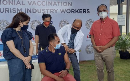 <p><strong>VAX FOR TOURISM WORKERS.</strong> DOH-7 epidemiologist Dr. Junjie Suazula administers a Covid-19 vaccine jab to a tourism worker at the Oakridge Business Park in Mandaue City on Friday (Sept. 24, 2021). National Task Force against Covid-19 chief implementer Sec. Carlito Galvez Jr., deputy implementer Vince Dizon and DOT Secretary Bernadette Puyat witnessed the ceremonial inoculation of the tourism workers. <em>(Photo courtesy of OPAV)</em></p>