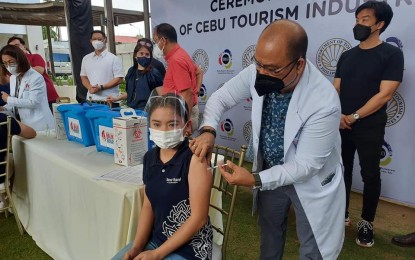 <p><strong>ECONOMIC DRIVERS.</strong> A tourism industry worker receives her Covid-19 vaccine shot at Oakridge Business Park in Mandaue City on Friday (Sept. 24, 2021). Tourism Secretary Bernadette Romulo-Puyat and National Task Force Against Covid-19 chief Secretary Carlito Galvez Jr. (standing, 3<sup>rd</sup> and 4<sup>th</sup> from left) attended the ceremonial inoculation activity. <em>(Photo courtesy of OPAV)</em></p>
