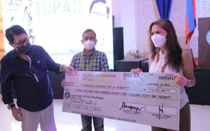 <p><strong>AID FOR WORKERS</strong>. Labor Secretary Silvestre Bello III (left) hands over a check replica of DOLE’s aid to North Cotabato beneficiaries to Governor Nancy Catamco (right) amounting to some PHP5.5 million. Looking on (center) is North Cotabato 3rd District Rep. Jose Tejada.<em> (Photo courtesy of North Cotabato PGO)</em></p>