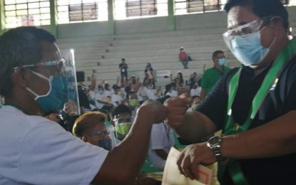 <p><strong>CARP BENEFICIARY</strong>. Agrarian Reform Secretary John Castriciones (right) does a fist bump with a farmer-beneficiary during the mass distribution of certificates of land ownership award in rites held at the municipal gym of Pontevedra, Negros Occidental on Thursday (Sept. 30, 2021). Some 7,268 agrarian reform beneficiaries received titles to 7,709 hectares of land in Negros Occidental during the activity. <em>(Photo courtesy of DAR Negros Occidental II-South)</em></p>