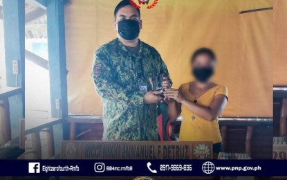 <p><strong>SURRENDERED</strong>. Alias "Claire" hands over a short firearm to Capt. Ricci Nikki Emmanuel Detruz of the Eastern Visayas police regional mobile force company on Wednesday (Sept. 29, 2021) in Carigara, Leyte. She surrendered to policemen after week-long negotiations. <em>(Photo courtesy of Philippine National Police)</em></p>