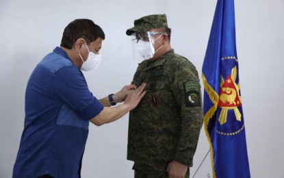 <p><strong>4TH STAR.</strong> President Rodrigo Duterte (left) dons the four-star rank to Gen. Jose Faustino Jr. on the sidelines of his visit at the Bicol International Airport, Daraga, Albay on Thursday (Oct. 7, 2021). Duterte has approved the appointment of Faustino and five other AFP senior officers effective September 15. <em>(Photo courtesy of AFP)</em></p>