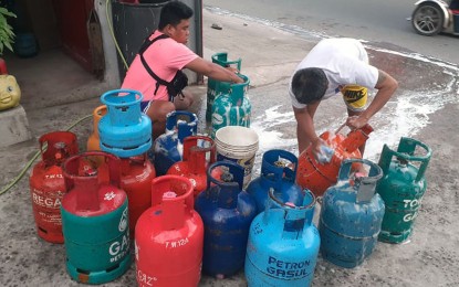 <p><strong>LPG PRICE HIKE.</strong> Workers wash liquified petroleum gas (LPG) tanks at their store in Barangay 176, Langit Road Phase 1, Bagong Silang-Kanan, Caloocan City in October 2021. Prices of liquefied petroleum gas increased by more than PHP11 per kilogram starting Wednesday (Feb. 1, 2023).<em>(PNA photo by Ben Briones)</em></p>