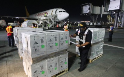 <p><strong>PFIZER JABS.</strong> A Bureau of Customs official inspects boxes of government-procured Pfizer vaccine doses transported by cargo plane Air Hongkong at the Ninoy Aquino International Airport Terminal 3 in Pasay City on Thursday night (Oct. 7, 2021). A total of 797,940 doses arrived at NAIA while the rest of the total 1,003,860 doses were shipped to Cebu and Davao. <em>(PNA photo by Avito C. Dalan)</em></p>