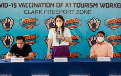 <p><strong>VAX FOR TOURISM WORKERS</strong>. Tourism Secretary Berna Romulo-Puyat (center) is joined by National Task Force Against Covid-19 Deputy Chief Implementer Secretary Vince Dizon (left), and Clark Freeport Zone president and CEO Manuel Gaerlan (right) during the vaccination of A1 tourism workers in Clark, Pampanga on Saturday (Oct. 9, 2021). Puyat returned to Pampanga to oversee the vaccination of some 518 tourism workers employed in accommodation establishments used as quarantine or isolation facilities in Central Luzon. <em>(Photo by DOT Philippines)</em></p>