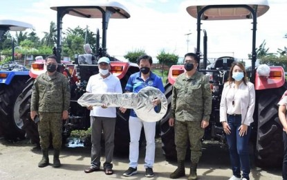 <p><strong>BDP PROJECT TURN-OVER</strong>. Escalante City Mayor Melecio Yap Jr. (center) hands over the symbolic key to a village official during the turnover of farm tractors to the seven insurgency-cleared barangays in the northern Negros city on Monday (Oct. 11, 2021). The ceremony was also attended by Philippine Army officials, including Brig. Gen. Inocencio Pasaporte (2nd from right), commander of 303rd Infantry Brigade, Lt. Col. J-jay Javines, commanding officer of 79th Infantry Battalion (left); and Fatima Daiz, head of the Department of the Interior and Local Government-Negros Occidental North Cluster. <em>(Photo courtesy of the City of Escalante)</em></p>