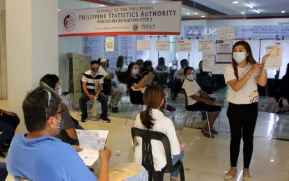 <p><strong>NAT'L ID SIGN-UP.</strong> An employee from the Philippine Statistics Authority explains the information that must be provided by applicants in their forms at a Philippine Identification System mall registration center in Imus, Cavite on Sept. 30, 2021. The national ID shall be a valid proof of identity that will simplify public and private transactions, enrolment in schools, and opening of bank accounts. <em>(PNA photo by Gil Calinga)</em></p>
