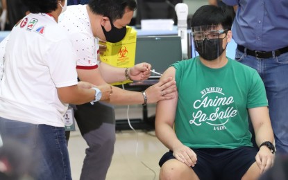 <p><strong>VACCINATED STUDENT-ATHLETES.</strong> De La Salle University student and taekwondo jin Dylan Reyes receives the coronavirus shot on Wednesday (Oct. 20, 2021) at the CHED office in Quezon City. More athletes, including those from NCAA-member schools, will have their turn to get vaccinated soon. <em>(PNA photo by Robert Alfiler)</em></p>
