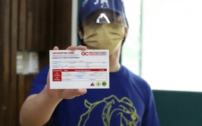 <p><strong>VAX CARD.</strong> A university student holds his vaccination card after being inoculated during the ceremonial vaccination of student-athletes at the Commission on Higher Education auditorium in Quezon City on Oct 20, 2021. The Department of Health on Tuesday (Nov. 14, 2023) said it is verifying the alleged leak of the country’s Covid-19 vaccination data stored in the World Health Organization.<em> (PNA photo by Robert Oswald P. Alfiler)</em></p>
