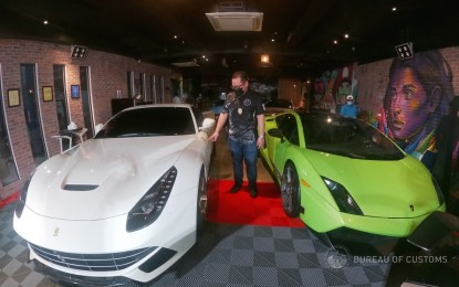 <p><strong>UNCOVERED.</strong> A Customs officer looks at two luxury cars discovered during an inspection of a showroom in Quezon City on Thursday (Oct. 21, 2021). The owners of the vehicles were given 15 days to present proper importation documents to avoid seizure and forfeiture, pursuant to Section 24 of the Customs Modernization and Tariff Act (CMTA). <em>(Photo courtesy of BOC)</em></p>