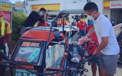 <p><strong>GAS SUBSIDY.</strong> Ilocos Norte Governor Matthew Joseph Manotoc fills up the gas tank for a tricycle driver from Barangay Raraburan, Laoag City on Friday (Oct. 22, 2021). Under the <em>Pantawid Pasada</em> program of the provincial government, each tricycle driver will receive PHP1,000 worth of gas subsidy while each jeepney driver will be given PHP1,500. (<em>Photo courtesy of Nikki Pilar</em>) </p>