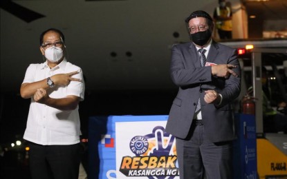 <p><strong>HIKING JABS DELIVERY.</strong> National Task Force Against Covid-19 chief implementer and vaccine czar, Secretary Carlito Galvez Jr. (left) and Russian Ambassador to Manila Marat Pavlov do the Resbakuna sign during the arrival of 400,000 doses of Sputnik V jabs at the NAIA Terminal 2 on Thursday (Oct. 21, 2021). Pavlov said Moscow is working slowly and steadily to increase deliveries of its Covid-19 jabs to Manila. <em>(PNA photo by Avito Dalan)</em></p>