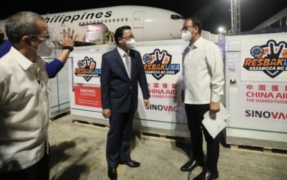 <p><strong>CHINA-MADE JABS.</strong> National Task Force Against Covid-19 chief implementer Secretary Carlito Galvez Jr. (right) and Chinese Ambassador Huang Xilian talk as boxes of Sinovac Covid-19 vaccine are unloaded from a Philippine Airlines flight at the Ninoy Aquino International Airport Terminal 2 on Sunday (Oct. 24, 2021) night. Two of the three million doses were government-procured while the rest of the vaccines were donated by China. <em>(PNA photo by Avito C. Dalan)</em></p>