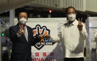<p><strong>CHINA-MADE JABS</strong>. National Task Force Against Covid-19 chief implementer, Secretary Carlito Galvez Jr. (right), and Chinese Ambassador Huang Xilian do the victory sign during the arrival of three million doses of the China-made Sinovac vaccine, one million of which were donated, at the Ninoy Aquino International Airport Terminal 2 on Oct. 24, 2021. Xilian said Friday (Dec. 10, 2021) the Chinese government is set to donate two million more doses of Sinovac to the Philippine government. <em>(PNA photo by Avito C. Dalan)</em></p>