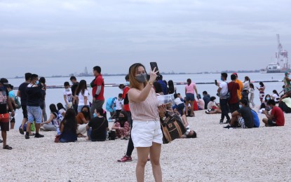 <p><strong>DOLOMITE BEACH</strong>. A woman takes a selfie at the Manila Baywalk Dolomite Beach along Roxas Boulevard in Manila City on October 25, 2021. The Department of Environment and Natural Resources moved its reopening to June 3, 2022 to give way to infrastructure completion and cleanup. <em>(PNA file photo)</em></p>