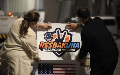 <p><strong>MORE JABS.</strong> National Task Force against Covid-19 chief implementer and vaccine czar Secretary Carlito G. Galvez Jr. (right) and US Embassy Manila Chargé d' Affaires Heather Variava (left) place a Resbakuna sticker on the box containing a portion of a total of 2,098,980 doses of Pfizer Covid-19 vaccine at the Ninoy Aquino International Airport (NAIA) Terminal 2 on Sunday evening (Oct. 31, 2021). The latest shipment of the American-made jabs is expected to beef up the country's vaccination efforts. <em>(PNA photo by Avito Dalan)</em></p>