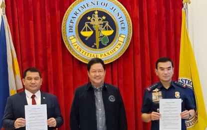 <p><strong>WORKING TOGETHER.</strong> NBI officer in charge-director Eric Distor (left) and PNP chief, Gen. Guillermo Eleazar (right) show a copy of the signed memorandum of agreement between the two agencies to operationalize probes of incidents of police abuses in anti-drug operations on Wednesday (Nov. 3, 2021). Justice Secretary Menardo Guevarra (center) witnessed the signing of the MOA. <em>(Photo courtesy of DOJ)</em></p>