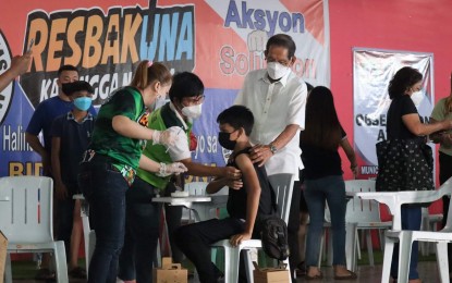 <p><strong>VAX DRIVE FOR MINORS.</strong> A minor gets his COVID-19 vaccine on Monday (Nov. 8, 2021) at the Municipal Recreation and Cultural Center in Santo Tomas, Davao del Norte as Mayor Ernesto Evangelista looks on. The local government rolled out its pediatric vaccination for minors aged 12 to 17 and encouraged parents to get their children vaccinated against the disease. <em>(Photo courtesy of Santo Tomas Municipal Information Office</em></p>