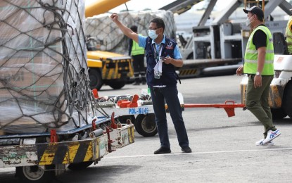 <p><strong>MORE COVID-19 VAX.</strong> A Department of Health personnel gives a full-stop signal to a forklift operator carrying some of the boxes of the Moderna Covid-19 vaccine at the Ninoy Aquino International Airport Terminal 1 in Parañaque City on Saturday (Nov. 13, 2021). The Philippines has so far received 123,258,340 doses of Covid-19 vaccines.<em> (PNA photo by Robert Oswald P. Alfiler)</em></p>