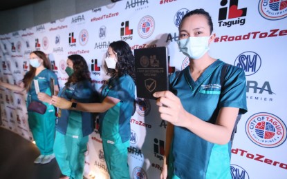 <p><strong>HEALTH WORKERS BOOSTERS. </strong>Health worker Daisy Marie S. Galdo, along with her co-employees, displays her vaccination card after she got a Pfizer booster shot at SM Aura Vaccination Hub, Samsung Hall in Taguig City on Nov. 17, 2021. President Rodrigo Duterte has signed into law a measure granting mandatory continuing benefits to public and private health workers during the coronavirus disease 2019 (Covid-19) pandemic and other future public health emergencies. <em>(PNA photo by Avito C. Dalan) </em></p>