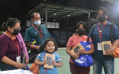 <p><strong>SENDOFF GIFTS.</strong> Fidel Boque’s three children, aged 16, 15, and 11, receive computer tablets under the Balik Probinsya, Bagong Pag-asa program at the National Housing Authority depot in Quezon City on Thursday (Nov. 18, 2021). The gadgets were donated by the Jaime V. Ongpin Foundation Inc. <em>(Photo courtesy of BP2)</em></p>