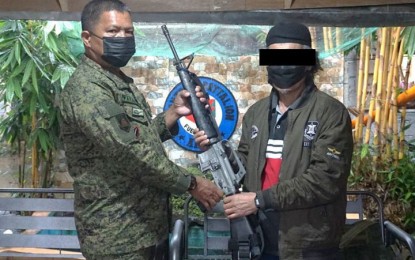 <p><strong>DAULAH ISLAMIYAH.</strong> A member of the Daulah Islamiyah-Maute Group (DIMG) hands over an M-16 Armalite rifle to Lt. Col. Fernando Payapaya, 51st Infantry Battalion (IB) commander (left), in Madalum, Lanao del Sur on Nov. 15, 2021. He was among three DIMG surrenderers who yielded to authorities some four years after the 2017 Marawi siege. <em>(Photo courtesy of the 51IB)</em></p>