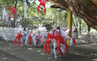 <p><strong>STARS OF CHRISTMAS</strong>. Village workers carry star lanterns (parol) to decorate the open multi-purpose area on Woodpecker Street, Barangay Kaligayahan, Novaliches-Fairview in Quezon City on Nov. 26, 2021. Health officials on Saturday (Dec. 4, 2021) urged the public to remain vigilant and as much as possible go virtual with holiday parties this December amid the threat posed by the Omicron coronavirus variant. <em>(PNA photo by Oliver Marquez)</em></p>