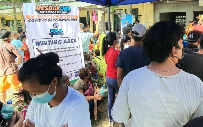 <p><strong>WAITING.</strong> Jennifer Samuel (left) and her partner, Gary Anacleto (on his back) wait for their numbers to be called in one of the 20 vaccination sites in Cagayan de Oro City on Monday (Nov. 29, 2021). Samuel said they took the opportunity to get vaccinated against Covid-19 in the government's national vaccination drive from November 29 to December 1 because they live in a far-flung community. <em>(PNA photo by Nef Luczon)</em></p>