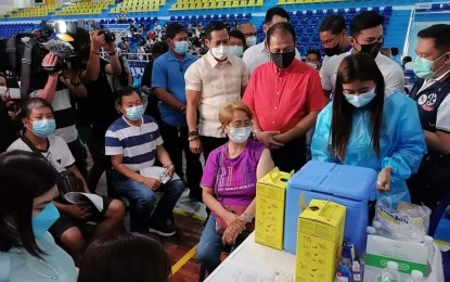 <p><strong>SITE VISIT.</strong> Vaccine czar Secretary Carlito Galvez Jr. (standing, in red) witnesses Day 2 operations of the national vaccination drive at the KB Gymnasium in Malolos City, Bulacan on Tuesday (Nov. 30, 2021). The first leg of the “Bayanihan, Bakunahan” campaign will end Wednesday (December 1). <em>(PNA photo by Manny Balbin)</em></p>