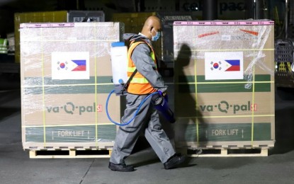 <p><strong>ADDED PROTECTION.</strong> An airport worker disinfects the cargo of 539,430 doses of the AstraZeneca Covid-19 vaccine at the Ninoy Aquino International Airport Terminal 3 in Pasay City on Tuesday (Nov. 30, 2021). The jabs were donated by South Korea through the COVAX Facility.<em> (PNA photo by Robert Oswald P. Alfiler)</em></p>