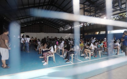 <p><strong>WAITING.</strong> Adults and teenagers queue up for vaccines at the multipurpose hall of Barangay Kaligayahan in Novaliches, Quezon City on Wednesday (Dec. 1, 2021). A total of 37.3 million Filipinos are already fully vaccinated as of December 2. <em>(PNA photo by Oliver Marquez)</em></p>
