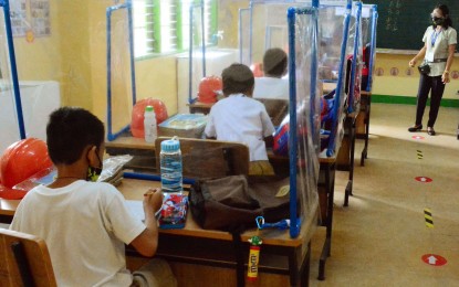 <p><strong>FIRST DAY HIGH</strong>. Grade 1 pupils sit on chairs with desks installed with plastic barriers while attending class at the La Huerta Elementary School in Parañaque City on Monday (Dec. 6, 2021). Some 28 public schools in Metro Manila joined the pilot run of face-to-face classes in the region. <em>(PNA photo by Avito Dalan)</em></p>