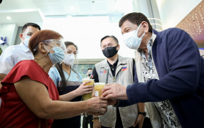 <p><strong>BE VACCINATED.</strong> President Rodrigo Roa Duterte gives out milk teas to people who received their vaccination against Covid-19 during the launching of the three-day vaccination campaign dubbed as National Vaccination Days: Bayanihan, Bakunahan 2021 at SM City Masinag in Antipolo City, Rizal on Nov. 29, 2021. Duterte is hopeful that the second simultaneous vaccine drive against Covid-19 on December 15-17 will finally persuade the unvaccinated to get their jabs. <em>(Presidential photo by Robinson Niñal)</em></p>