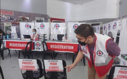 <p><strong>CONTINUING VACCINATION.</strong> A volunteer of the Philippine Red Cross arranges the chairs at the PRC multi-purpose hall in Zamboanga City as it serves as a vaccination center for pediatrics on Dec. 9, 2021. The City Health Office on Thursday said a total of 901,940 individuals have received their Covid-19 vaccines in the immunization campaign in the city.<em> (Photo courtesy of Zamboanga CIO)</em></p>