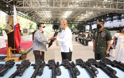 <p><strong>DONATION.</strong> Defense Secretary Delfin Lorenzana (middle) receives a firearm from LCS Group of Companies chairperson and Narvacan, Ilocos Sur Mayor Luis "Chavit" Singson during the turnover of donated firearms and equipment to the AFP in Camp Aguinaldo on Thursday (Dec. 9, 2021). The AFP received a total of 41 units of assorted firearms and accessories which will be distributed to various military units. <em>(Photo courtesy of AFP)</em></p>