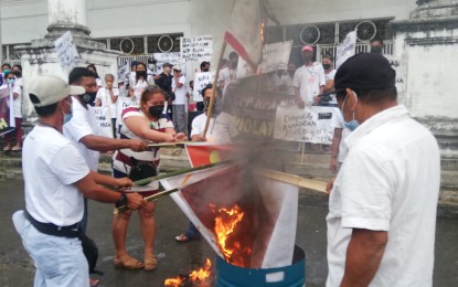 <p><strong>DENOUNCING INSURGENCY.</strong> Former members of New People’s Army front organizations burn rebel flags outside the People’s Center and Library in Tacloban City on Friday (Dec. 10, 2021). At least 152 formally disaffiliated from communist terrorist groups. <em>(PNA photo by Sarwell Meniano)</em></p>
