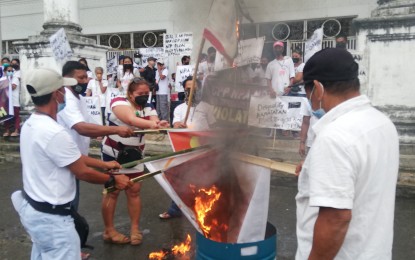 <p><strong>CUTTING TIES WITH THE NPA</strong>. Former members of front organizations of the New People's Army (NPA) torch flags during a mass disaffiliation in Tacloban City on Dec. 13, 2021. More than 2,000 members and staunch supporters of the NPA surrendered in Leyte, Southern Leyte, and Biliran provinces in 2021, stalling the group’s attempt to recruit new members in these provinces, the Philippine Army said on Friday (Jan. 7, 2022). <em>(PNA photo by Sarwell Meniano)</em></p>